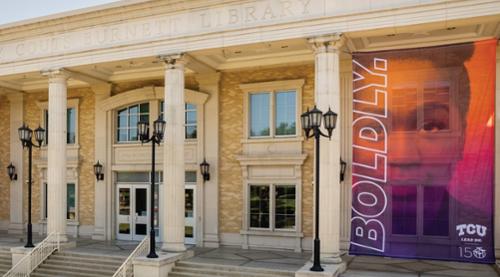 Outside of the library with a purple and orange banner that says boldly