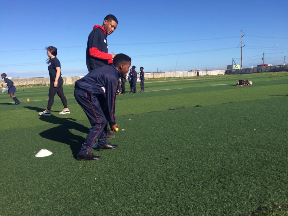 Devieonte watching over a child while they play a game on a green turf