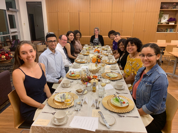 STEM Scholars seated at long dining table with full table settings and Anne VanBeber at the head of the table