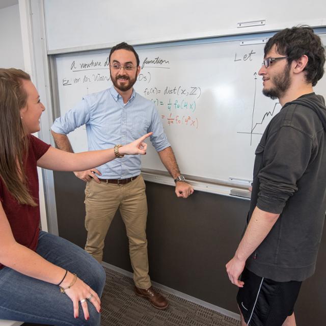 professor teaching students at a white board