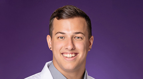 Daniel wearing his white TCU School of Medicine coat in front of a purple background