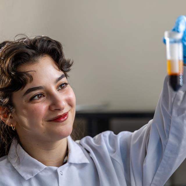 Female student performing a research experiment with a test tube.