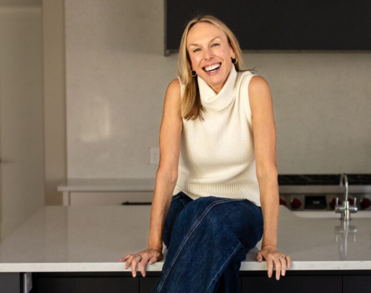 Psychologist Sarah Hill sits on a kitchen counter.