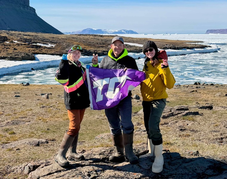 Cami Middlebrooks, Matt Chumchal and Nicole Fordree holding a TCU flag in the arctic