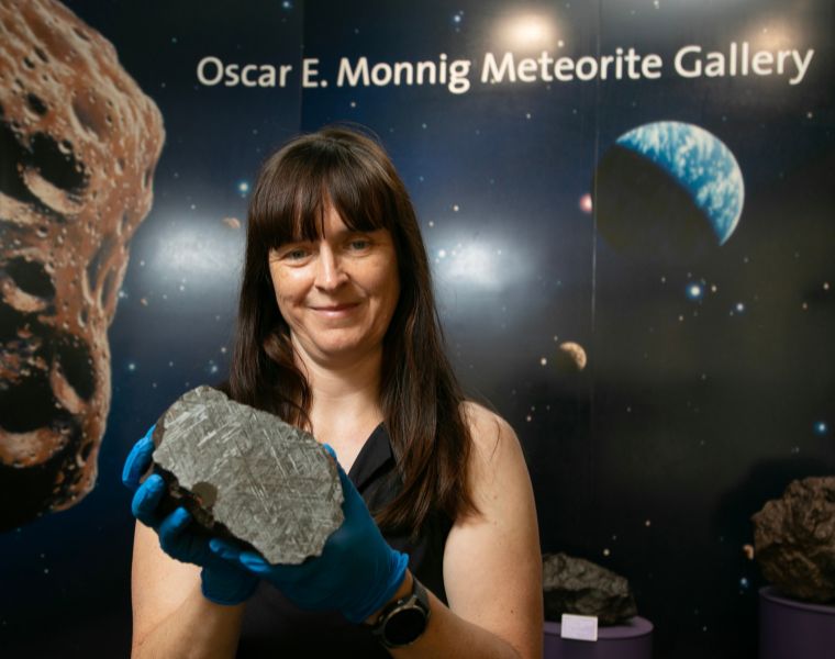 Rhiannon Mayne shows off a meteor in front of the Monnig Meteorite Gallery.